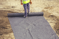 Picture of a man rolling out synthetic geotextile