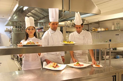 Three chefs with food dishes in a restaurant kitchen