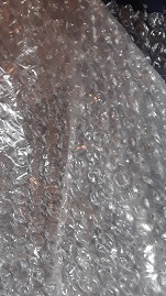 Close-up image of a sheet of transparent bubble wrap, showing its textured surface with air-filled pockets.